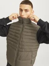 Chaleco acolchado verde militar sin mangas, con cuello alto, cierre frontal con cremallera y bolsillos delanteros.