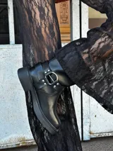 Botas negras de cuero con plataforma, hebillas y detalles metálicos.