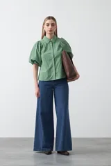 Camisa blanca de algodón con cuello camisero y mangas cortas abullonadas. Presenta un corte relajado y cierre frontal de botones.