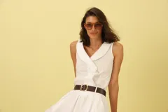 Camisa blanca sin mangas con cuello solapa y cierre frontal con botones.