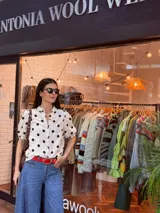 Camisa blanca de muselina con estampado de lunares negros, manga corta abullonada y botones al frente.
