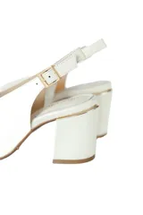Sandalias de cuero color blanco hueso, con punta cuadrada y escote en el empeine. Tienen un tacón cuadrado de 7 cm y tira trasera con hebilla. El interior es de cuero color beige.