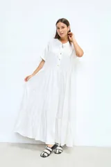 Vestido largo blanco de lino, corte amplio, con cuello mao, mangas cortas y volados en la falda.