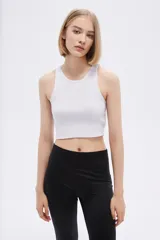 Top blanco sin mangas de poliéster, de punto canalé, al cuerpo y con cuello a la base.