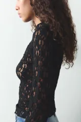 Camiseta negra de encaje con cuello alto y mangas largas.