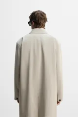 Gabardina color beige de corte relaxed fit, confeccionada en tejido italiano repelente al agua. Tiene cuello solapa, manga larga con puños abotonados, bolsillos de vivo en la cadera, bolsillo interior y abertura en la espalda.