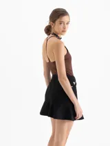 Minifalda de denim negro con cinco bolsillos tradicionales y un volado en el ruedo.