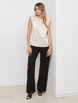 Blusa de gasa color beige con textura labrada, sin mangas, con hombreras internas y abertura en la espalda con botón.