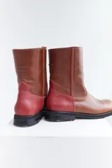 Botas de media caña color marrón de cuero vacuno, con detalle de costuras en la capellada y contrafuerte color bordó. Suela de caucho con taco bajo.