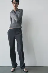Pantalón de vestir gris oscuro de tiro bajo, con trabillas en la cintura, bolsillos delanteros y traseros, raya planchada y pierna recta.