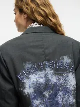 Blazer gris oscuro de lana con cuello solapa y cierre con botones. Presenta pedrería decorativa en la parte delantera y trasera.