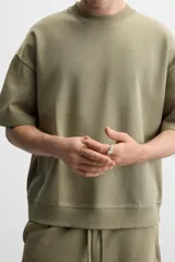 Sudadera negra de corte relaxed fit, confeccionada en tejido interlock de algodón con elasticidad. Tiene cuello redondo, manga corta y bajo acabado en rib.