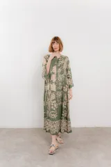 Vestido largo azul con estampado floral en tonos beige, confeccionado en viscosa. Presenta escote en V, botonadura completa en el frente y mangas largas con volados.