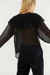 Blusa de gasa azul marino traslúcida con volados en los hombros y mangas largas abullonadas.