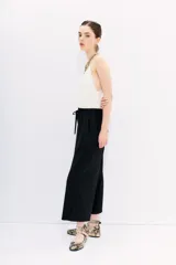 Pantalón crop negro de corte amplio, con cintura elástica ajustable con cordón y bolsillos laterales.