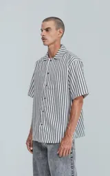 Camisa de manga corta con cuello abierto y corte oversize, a rayas verticales blancas y negras.