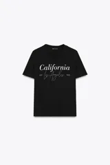 Camiseta negra de algodón con cuello redondo, manga corta y estampado frontal con la frase "California Los Angeles EST 1895" en color blanco.