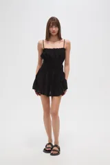 Vestido corto negro de algodón con breteles finos, escote recto, corte holgado, cintura elastizada y volados en el ruedo.