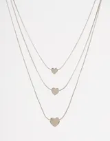 Collar multicadena plateado con tres cadenas de diferentes largos, cada una con un dije de corazón.