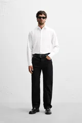 Camisa blanca de corte slim fit, confeccionada en algodón, con cuello italiano, mangas largas con puños abotonados y cierre frontal con botones.