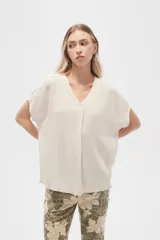 Blusa color crema de lino, holgada, con cuello en V y mangas cortas.