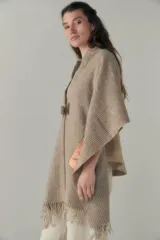 Chal de lana fina sin teñir, con calce en hombros, abrochadura con alamar de fieltro, bolsillos de cuero y terminación con flecos. Diseño exclusivo de Don Baez, hecho en Uruguay.