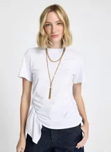Remera blanca de punto con cuello redondo, mangas cortas, frunce lateral y bajo asimétrico.