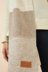 Chal unisex de lana fina sin teñir, realizado con retazos de telas diseñadas por Don Baez. Presenta una grifa de cuero aplicada.