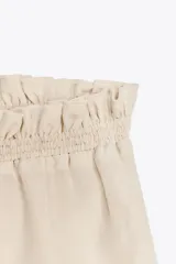 Falda midi color crudo confeccionada en tejido de viscosa, con cintura elástica y volantes en capas.