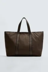 Bolso tipo shopper color marrón, fabricado en tejido de algodón con detalles en piel. Asas fabricadas en piel y algodón. Compartimento principal con cierre mediante imán. El interior cuenta con un bolsillo con cierre mediante cremallera y un bolsillo plano.