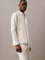 Camisa de manga larga color blanco hueso, confeccionada en lino y algodón. Tiene cuello clásico, cierre con botones y un bolsillo en el pecho.