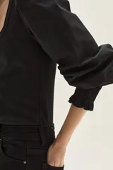 Top negro de calce al cuerpo con escote cuadrado amplio. Mangas largas abullonadas con puños elastizados.