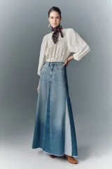 Falda larga acampanada de denim rígido con diseño patchwork en distintos tonos de azul y ruedo desflecado.