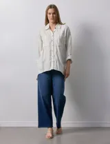 Camisa de lino a rayas verticales color crema, con cuello con solapa, abertura central con botones, bolsillos delanteros y mangas 3/4 regulables con presilla y botón.