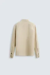 Camisa de manga larga color celeste claro, con cuello solapa y cierre frontal de botonadura. Presenta una textura sutil en el tejido.