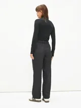 Pantalón negro de vestir con finas rayas verticales blancas, corte recto y tiro alto.