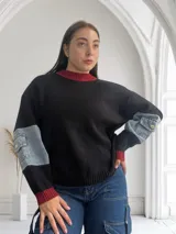 Sweater negro de punto con cuello y puños acanalados en color rojo. Mangas largas con detalle de denim.