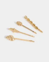 Set de cuatro horquillas doradas para el pelo con diseño de conchas marinas.