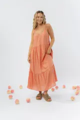 Vestido largo color durazno, con breteles finos y escote en “V”. De corte amplio y con vuelo en el ruedo. Confeccionado en gasa de algodón liviana y con textura.