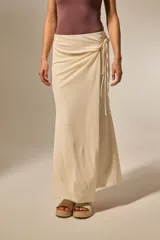 Falda larga negra con detalle de nudo lateral y tiras colgantes, de corte ajustado en la parte superior y ligeramente acampanado en el ruedo.