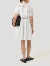 Vestido corto blanco de lino y viscosa, con cuello mao, mangas cortas, cierre frontal con botones, encaje en la parte superior y en la cintura, y forro a tono.