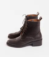 Bota corta de cuero color marrón claro, con cordones y detalles de perforaciones. Tiene un pequeño taco de madera.