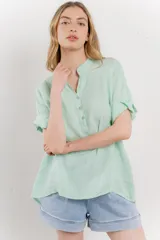 Blusa blanca de lino con escote en V abotonado y mangas cortas arremangadas.