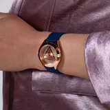 Reloj Guess Iconic con caja redonda de acero tono oro rosa de 34 mm y esfera a juego con detalles brillantes. Correa de silicona azul y logotipo triangular “G” en el centro.