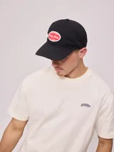Gorra de lona lavada color azul con visera curva y parche bordado con el logo de Rusty en el frente.