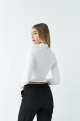 Top blanco de manga larga con cuello alto y abertura en el pecho. Corte ajustado y tejido elastizado.