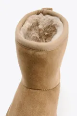 Botín color beige de caña baja, con interior de efecto pelo y suela tipo flatforma.