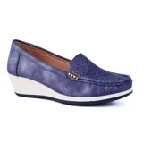 Zapato Korium color beige con capellada lisa, detalle de perforaciones y aplique metálico dorado. Tiene taco corrido blanco y suela marrón.