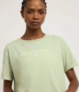 Remera de manga corta, cuello redondo y calce oversized, color verde claro con efecto lavado. Presenta un estampado serigráfico en la espalda con un vaso de bebida helada y texto que dice "i'm powered by MATCHA FUEL ONLY daily clean energy CLUB".