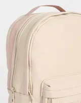 Mochila color beige de tela deportiva con textura. Tiene correa regulable, manija superior, cierre superior, doble bolsillo frontal con cierre y pullers, y bolsillos laterales.